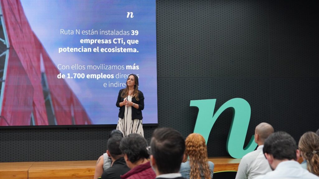 Edificio de Ruta N en Medellín con personas colaborando en un entorno tecnológico moderno, representando la innovación social y alianzas globales.