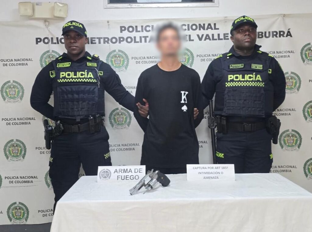 Dos oficiales de la Policía Nacional de Colombia custodian a un hombre detenido