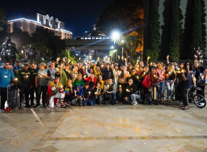 Grupo de personas con velas encendidas durante un recorrido cultural y patrimonial nocturno en la Plaza Botero comuna 10