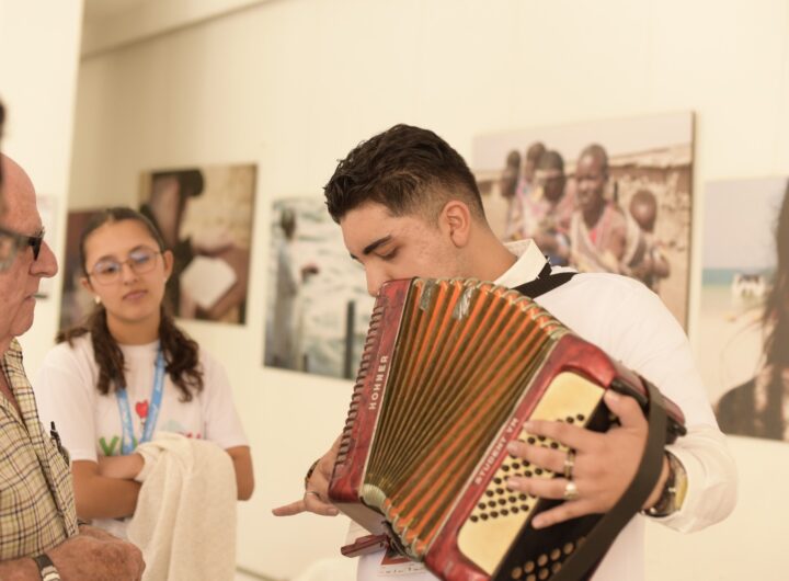 Un joven músico toca un acordeón rojo marca Hohner durante una exposición fotográfica en un evento cultural en Medellín.