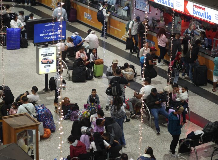 Vista elevada de la sala de espera en la Terminal de Transporte de Medellín, mostrando viajeros con equipaje y decoraciones navideñas de luces.
