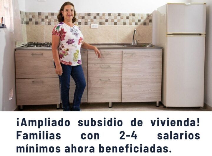 Mujer sonriente en cocina moderna con estufa, lavaplatos y nevera, representando la ampliación del subsidio de vivienda para familias con 2-4 salarios mínimos en Medellín.