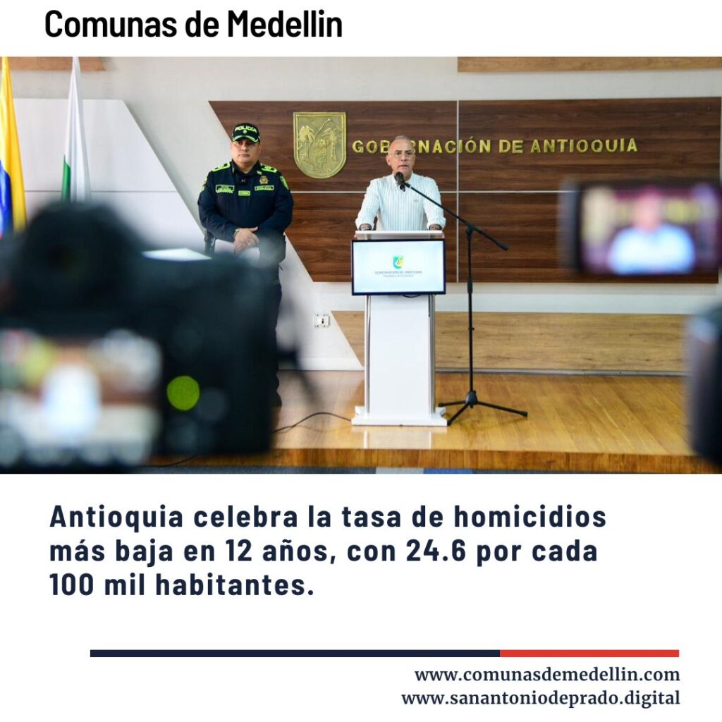 Conferencia de prensa con orador en podio y policía, anuncio de Antioquia celebrando la tasa de homicidios más baja en 12 años con 24.6 por cada 100 mil habitantes.