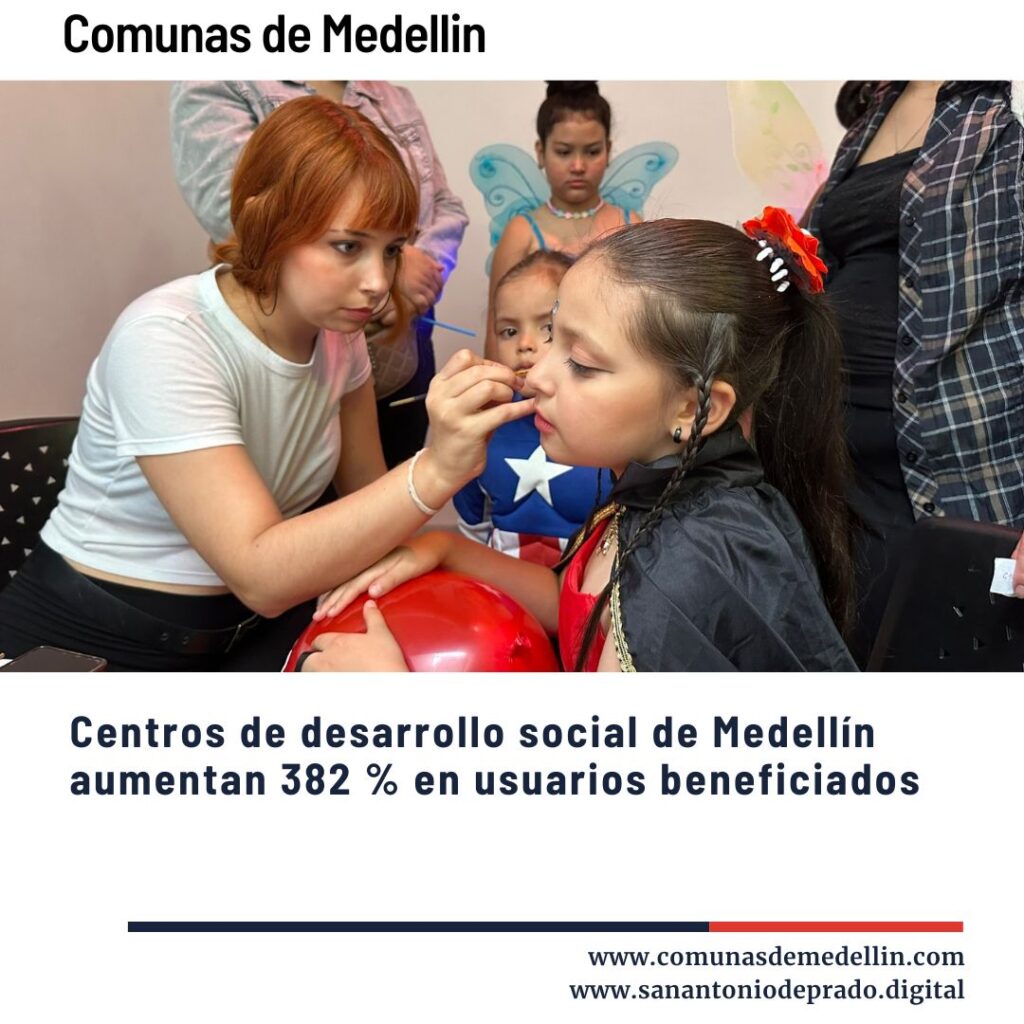 Voluntaria pintando la cara a una niña disfrazada en actividad recreativa de un centro de desarrollo social en Medellín, con otros niños al fondo.