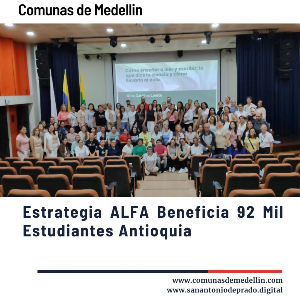 Grupo numeroso de docentes y profesionales de la educación posando en un auditorio de Medellín, sonrientes frente a una pantalla con la ponencia "Cómo enseñar a leer y escribir: lo que dice la ciencia y cómo llevarlo al aula" de Gina Catalina Loaiza, en evento de la estrategia ALFA para alfabetización inicial.