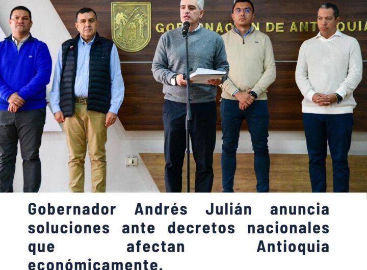 Funcionarios y líderes en conferencia de prensa sobre impacto de 1.5 billones en Antioquia por emergencia económica y alza salarial del Gobierno nacional, fondo con escudo de Gobernación - Comunas de Medellín.