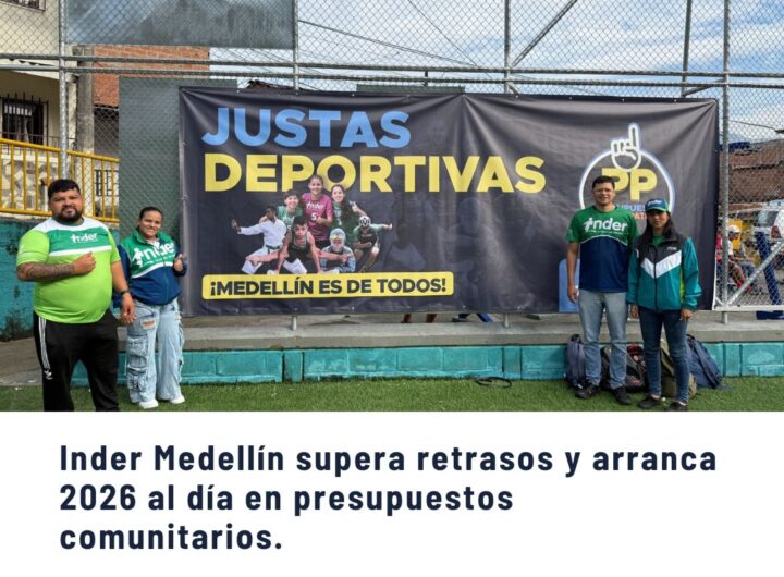 Grupo de personas posando frente a un banner de "Justas Deportivas" del Inder Medellín en una cancha comunitaria, destacando que el Inder supera retrasos y arranca 2026 al día en presupuestos comunitarios.