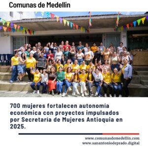 Grupo grande de mujeres sonrientes posando en escaleras al aire libre con banderas de colores, celebrando el fortalecimiento de la autonomía económica de 700 mujeres en Antioquia durante 2025 por la Secretaría de Mujeres.